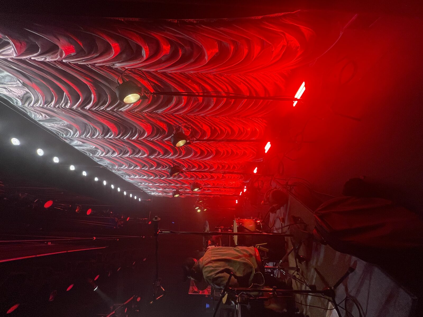 Silver Austrian swoop drape wide angle from stage with red lighting