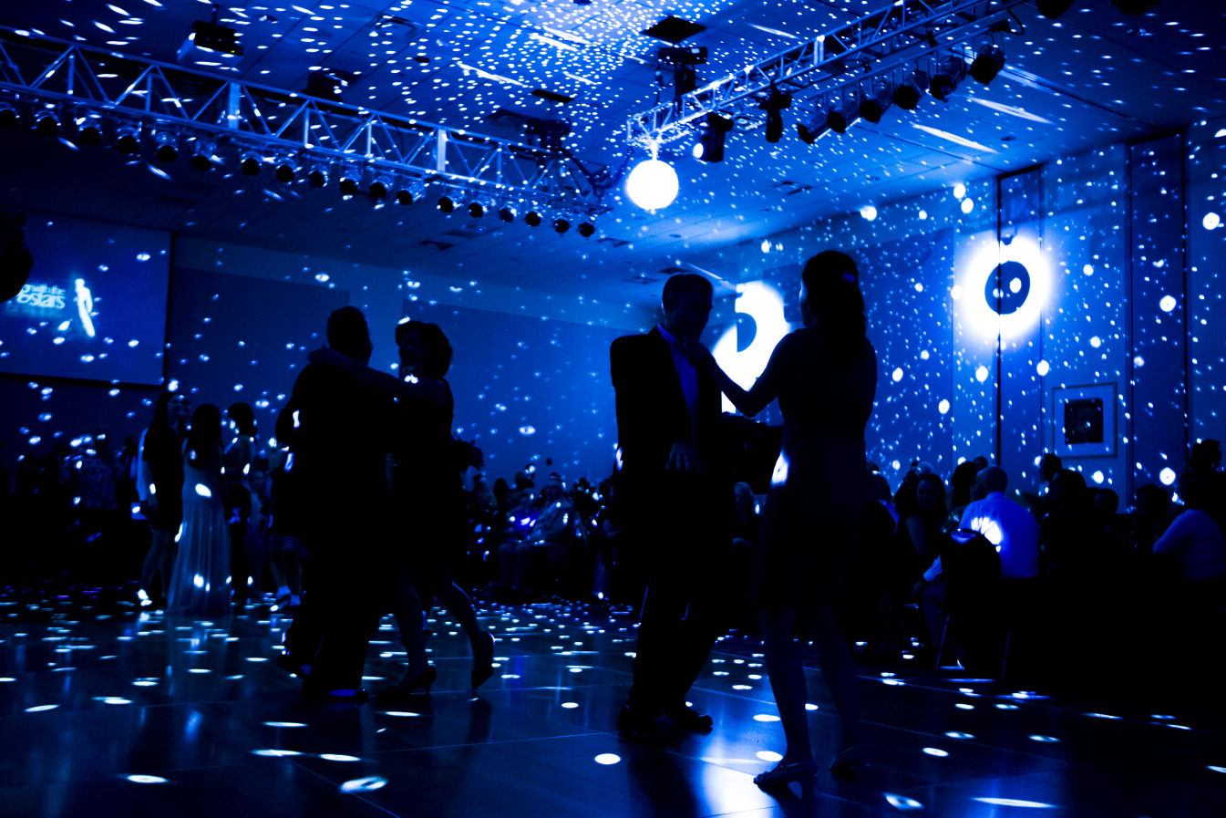 Dance floor atmosphere with dramatic blue lighting and drape backdrop