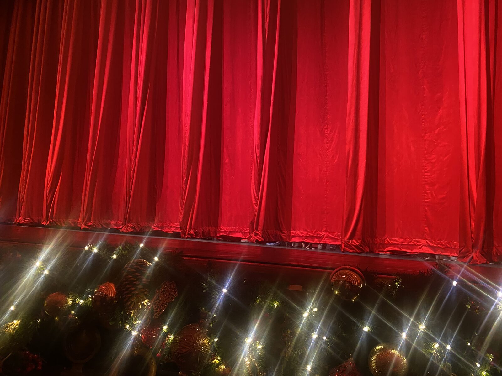 Red drape backdrop with holiday decorations and warm lighting